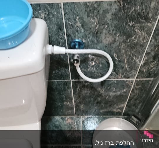 אסלה עם צינור מים ודלי על הרצפה